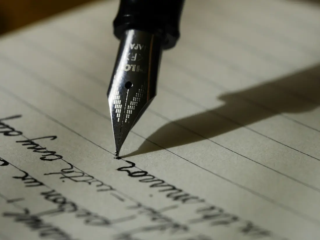 Pluma escribiendo a mano sobre papel